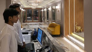 A modern hotel lobby with a reception desk, computers, a chandelier, and a ceiling fan. - Bawa Hotel (Kanpur)