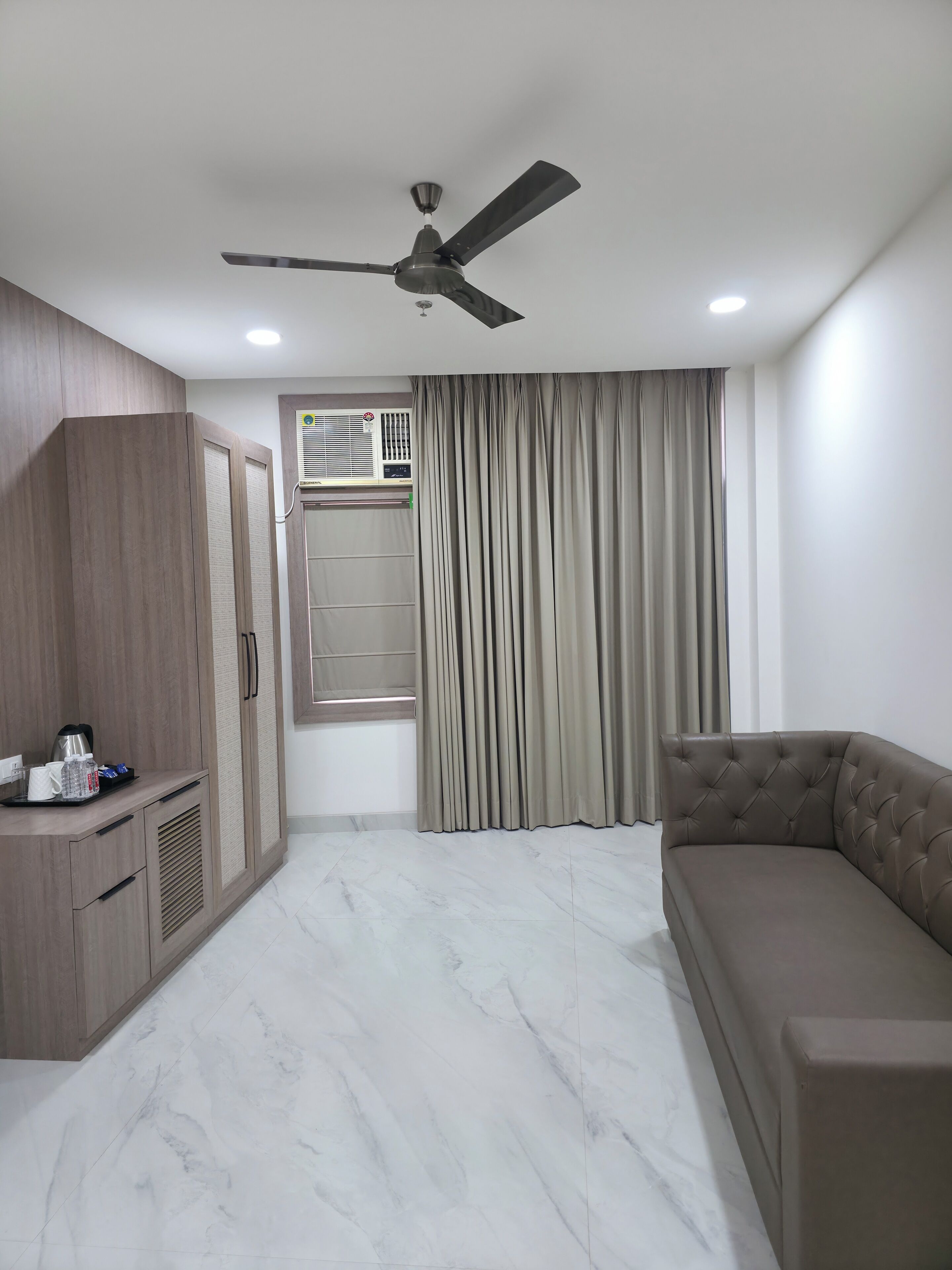 A modern room with a ceiling fan, a built-in air conditioning unit, a sofa, and a wardrobe.