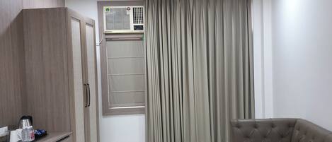 A modern room with a ceiling fan, a built-in air conditioning unit, a sofa, and a wardrobe.