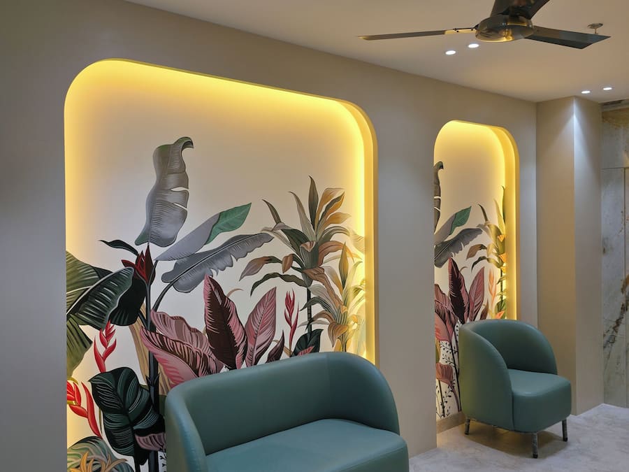 Una sala de estar moderna con un sofá color turquesa, un ventilador de techo y un mural con hojas y pájaros tropicales.