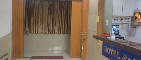 A hotel reception area with a polished tile floor, a reception desk, and a large mirror reflecting the interior.