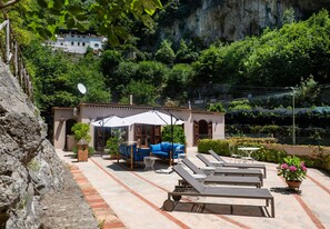 Un patio con mobiliario exterior, una pérgola y vistas a un paisaje montañoso.
