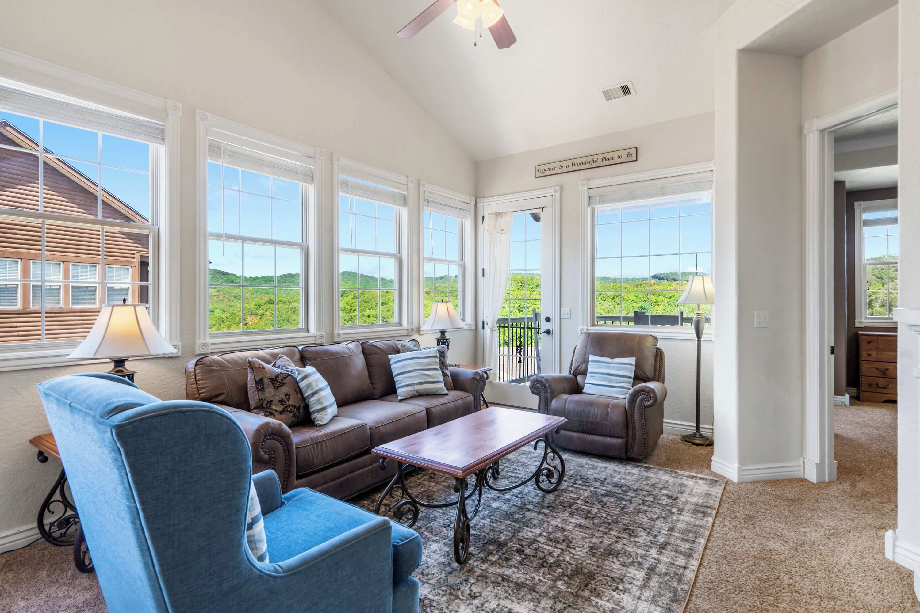 A spacious living room with a large window, a ceiling fan, and a view of the outdoors.