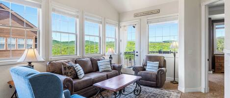 A spacious living room with a large window, a ceiling fan, and a view of the outdoors.