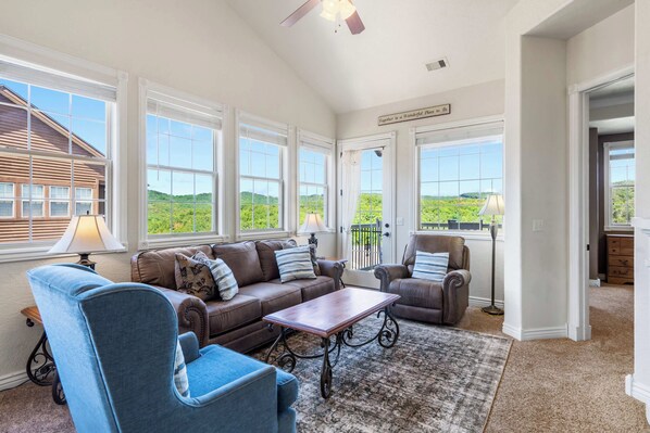 A spacious living room with a large window, a ceiling fan, and a view of the outdoors.