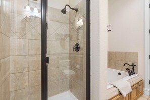 A bathroom with a glass-enclosed shower, a bathtub, and a vanity with a towel.