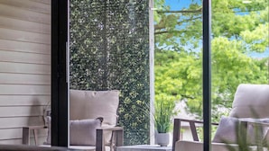 Un espace extérieur accueillant, aménagé avec deux chaises et une petite table, offrant une vue sur un jardin bien entretenu et des arbres.
