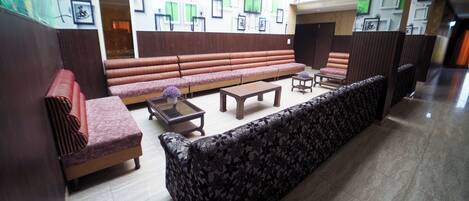 A lobby with a long sofa, a smaller sofa, a coffee table, and a chair.