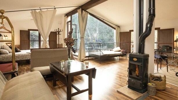 Un amplio salón con un ventanal grande, una chimenea, un sofá, una mesa de comedor y una cama.