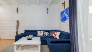 Un salon moderne avec un canapé bleu foncé, une table basse blanche et des coussins aux motifs marins.