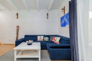 Ein modernes Wohnzimmer mit einem dunkelblauen Sofa, einem weißen Couchtisch und Kissen im maritimen Stil.