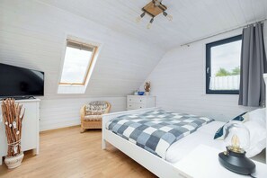 Un dormitorio con cama, televisión, ventana y ventilador de techo.