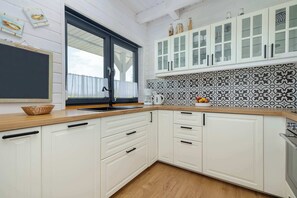 A kitchen with white cabinets, a black-framed window, and a patterned backsplash.
