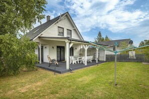 A house with a covered patio, a lawn, and a fence in the background.