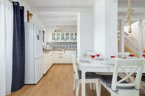 Eine moderne Küche mit weißen Schränken, einem Esstisch für zwei Personen und einer Treppe, die in einen oberen Bereich führt.