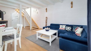 Un salon moderne avec un canapé blanc, une table basse blanche et un escalier menant à un niveau supérieur.