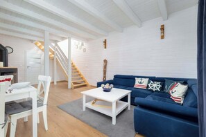 A modern living room with a white sofa, a white coffee table, and a staircase leading to an upper level. - Spacious Apartment with 3 Bedrooms | Parking and Fireplace (Zastań)