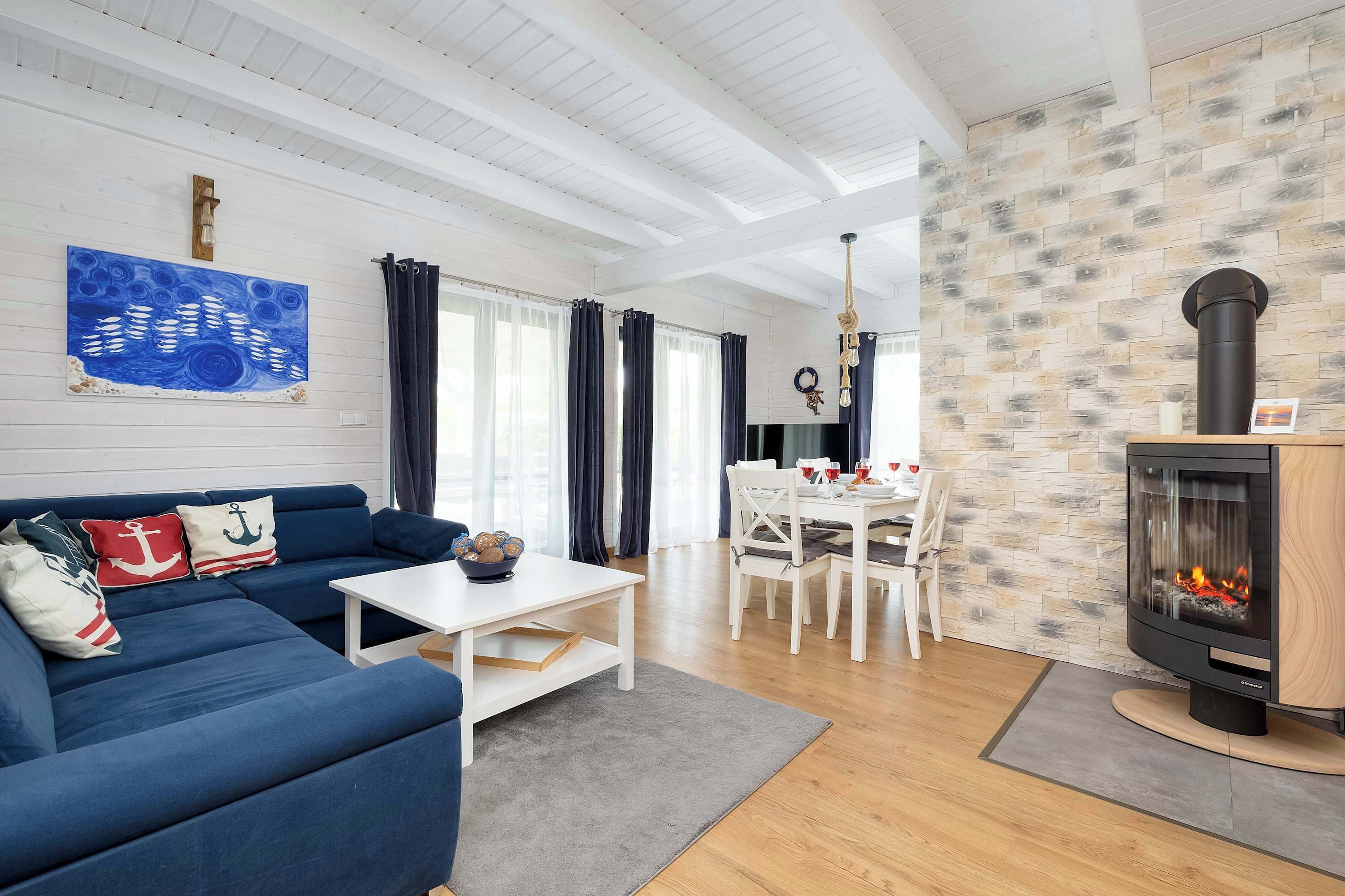 A cozy living room with a blue sofa, a fireplace, and a dining table in the background.