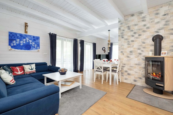 A cozy living room with a blue sofa, a fireplace, and a dining table in the background.