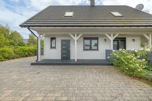 A single-story house with a dark roof, white exterior walls, and a covered porch.