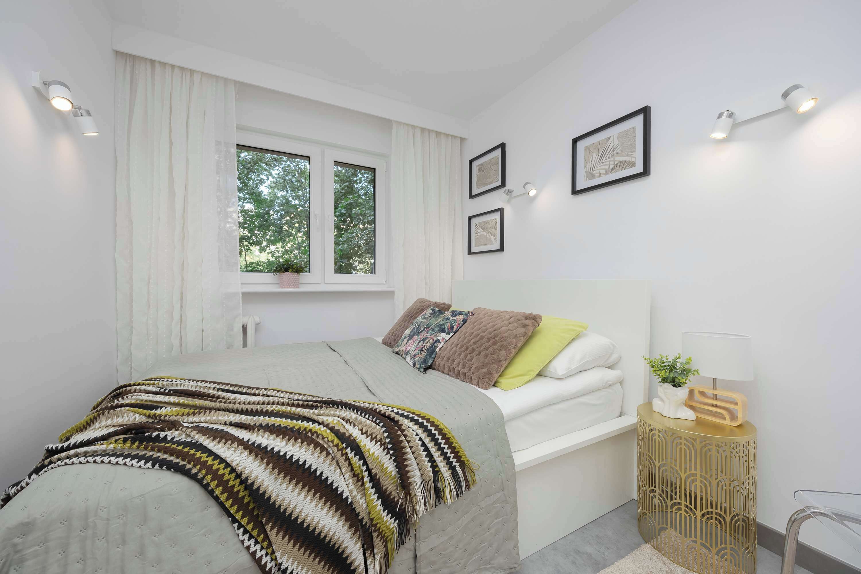 A modern bedroom with a bed, bedside table, and window.