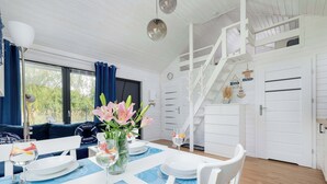 A dining area with a table set for four, a staircase, and a view of the outdoors.