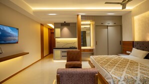 Ett modernt hotellrum med en säng, ett skrivbord, en stol, en TV och en garderob.