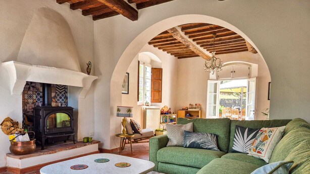 A cozy living room with a green sofa, a fireplace, and a view of the outdoor patio.