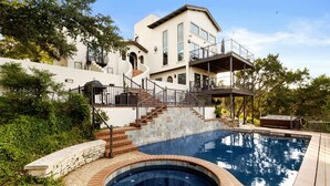 Ein zweistöckiges Haus mit Pool, Whirlpool und einer Treppe, die zu einem Balkon führt.