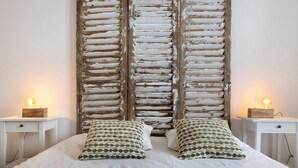 A bed with white bedding, two bedside tables with lamps, and a wall with a distressed wooden panel design.