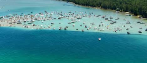 An aerial view of a coastal area with numerous boats and a small island with dense forestation.