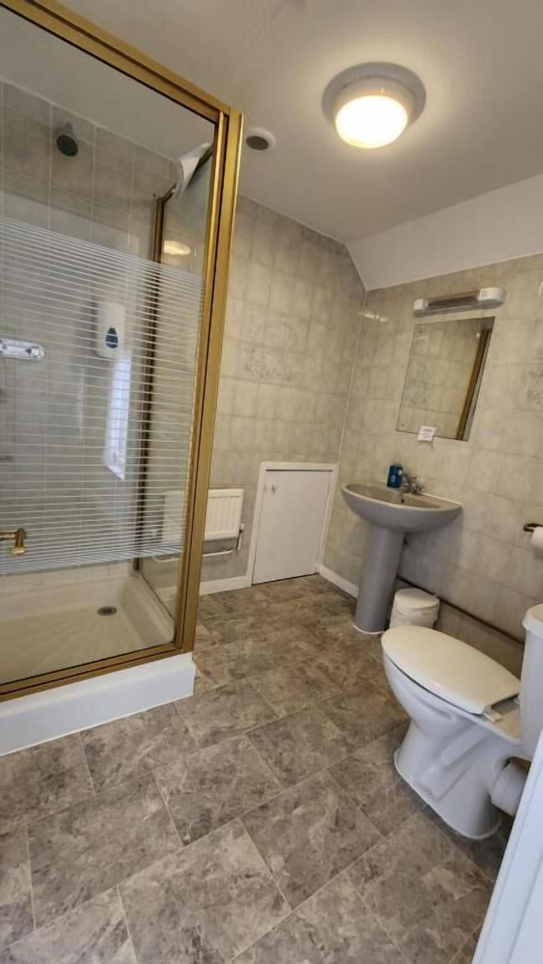 A bathroom with a glass-enclosed shower, a sink, and a toilet.
