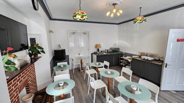A compact kitchen with modern appliances, a dining area with round tables and chairs, and a small bar area.