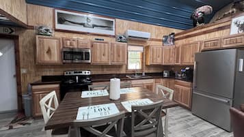 A modern kitchen with wooden cabinets, stainless steel appliances, and a dining area with a table displaying 'live love eat' placemats.