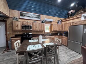 Una cocina moderna con armarios de madera, electrodomésticos de acero inoxidable y una zona de comedor con un mantel mostrando posavasos con la inscripción 'live love eat'.