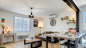 Ein modernes Wohnzimmer mit Essbereich, einer Couch, einem Couchtisch und einer Wanduhr.
