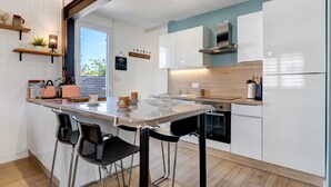 Eine moderne Küche mit Kochinsel, Barhocker und Blick ins Freie.