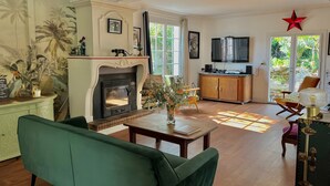 A living room with a fireplace, green sofa, wooden coffee table, and a TV. - Villa Esterel, for 14 people, located 200 m from the beach (La Faute sur Mer)