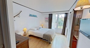 Een slaapkamer met een bed, bedlampen, een bureau, een televisie en een bord waarop 'VACANCES' staat.