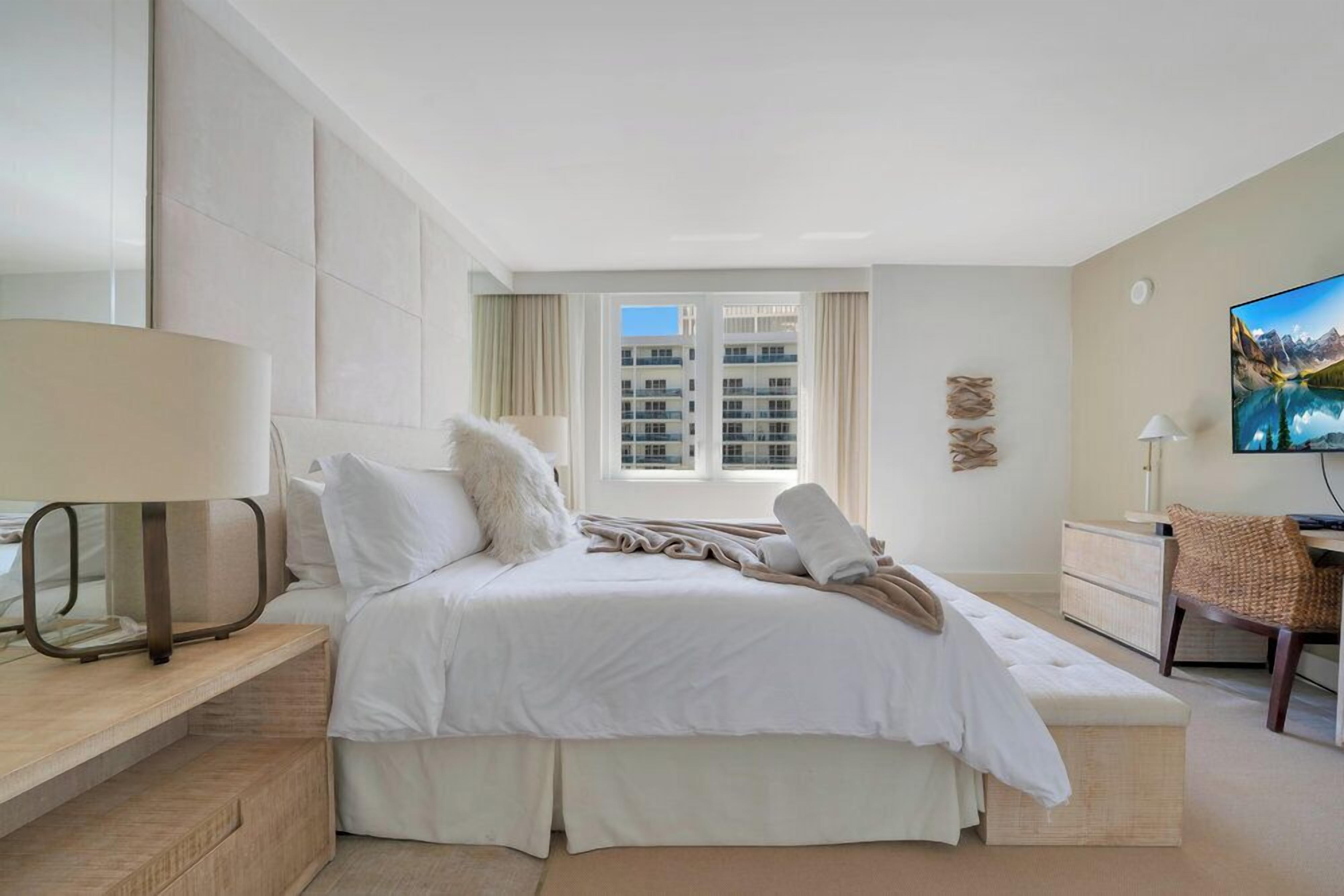 Une chambre d’hôtel avec un grand lit, un bureau, une chaise et un téléviseur.