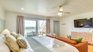 Camera d'albergo con un letto grande, una poltrona, una TV e un balcone con vista.