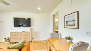 Un soggiorno moderno con un tavolo da pranzo in legno, un divano e una TV fissata alla parete.