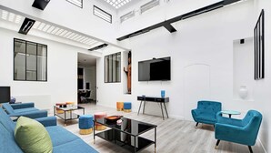 Una sala de estar moderna con un sofá modular, una mesa de centro de vidrio y dos sillones azules.