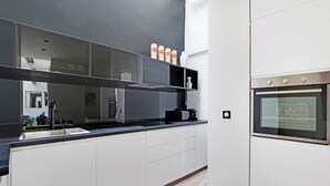 Una cocina moderna con armarios blancos, una encimera negra y un horno de acero inoxidable.