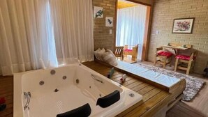 Eine Holzhütte mit Whirlpool, Holzboden und einem Essbereich mit Tisch und Stühlen.