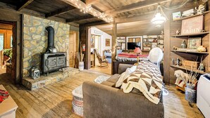 A cozy cabin interior with a stone wall, wooden beams, a fireplace, a sofa, and a dining area. - Trail Access & Tranquil Setting: Franklin Retreat! (Franklin)
