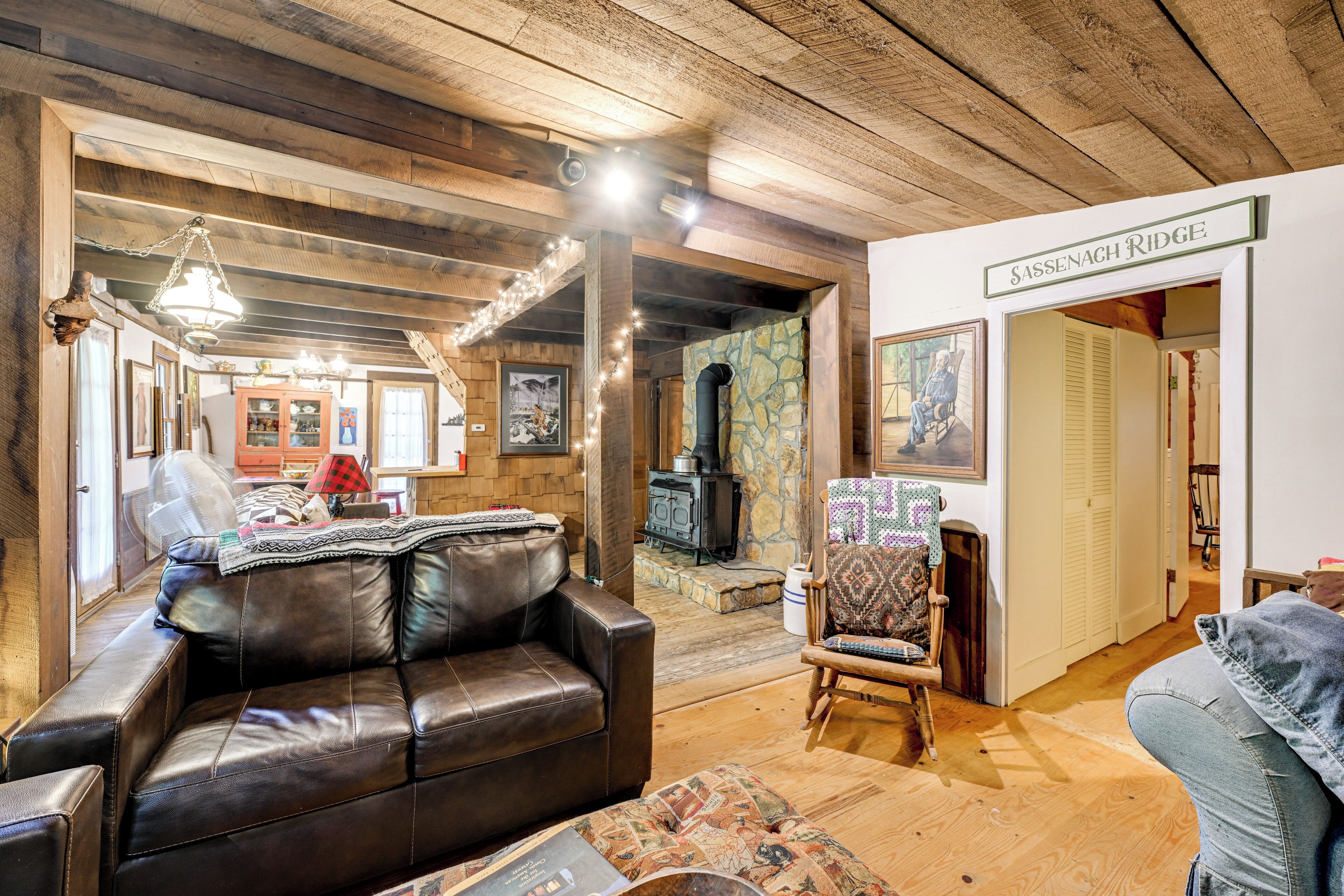A cozy living room with a leather sofa, a patterned armchair, and a stone fireplace.