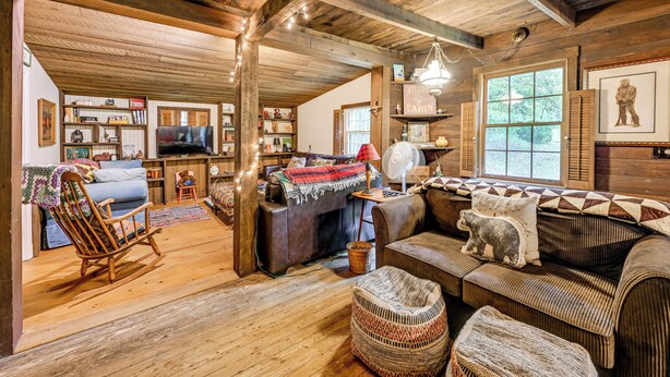 A cozy cabin interior with a wooden floor, a rocking chair, a sofa, and a television in the living area. - Trail Access & Tranquil Setting: Franklin Retreat! (Franklin)