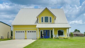 Una casa gialla con una porta blu e due cancelli per garage.