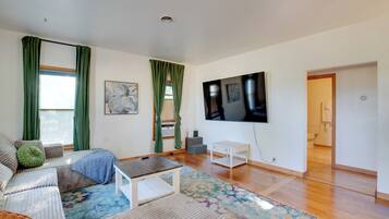 A spacious living room with a sofa, a coffee table, and a TV mounted on the wall.